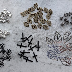 Assortiment de pendentifs, connecteurs et perles en métal. Noir, bronze, argent, acier inoxydable