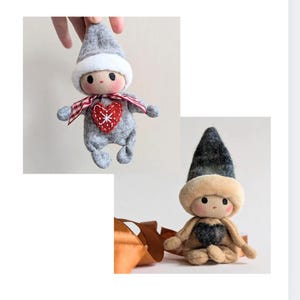May include: Two handmade felt Christmas elf dolls. One doll is gray with a red heart and a white snowflake design. The other doll is tan with a black heart. Both dolls have black eyes and red yarn mouths.