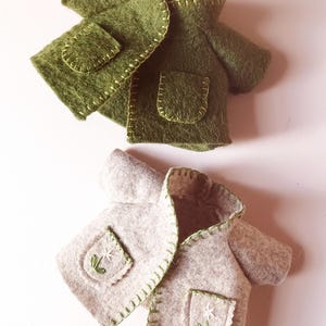 May include: Two felt jackets with pockets. One is green and the other is beige with embroidered flowers.