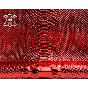 May include: Close-up of a vibrant red leather material with a textured, scale-like pattern. The image features a glossy finish and a logo in the upper left corner that reads "LEATHER AA ITALIAN LEATHER COMPANY."