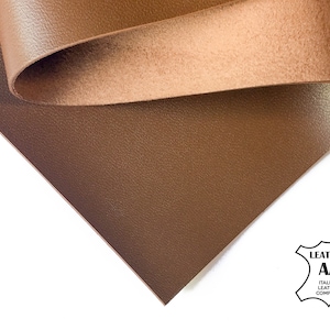 May include: A close-up of a brown leather sheet with a textured surface. The leather is folded over, revealing the underside. The image includes a logo that reads "Leather AA Italian Leather Company".