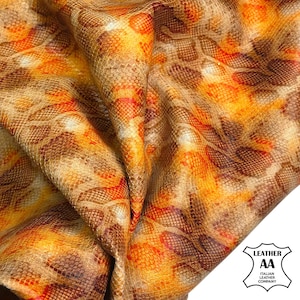 May include: A close-up of folded leather with a snakeskin design. The material displays a mix of brown, orange, and red tones, giving a textured and detailed look. The image includes a logo for an Italian leather company.