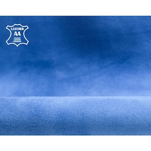 May include: A close-up of a textured, blue leather material. The image features a gradient of blue hues, with a lighter shade at the bottom and a darker shade at the top. The upper left corner displays a white logo with the text "LEATHER AA ITALIAN LEATHER COMPANY".
