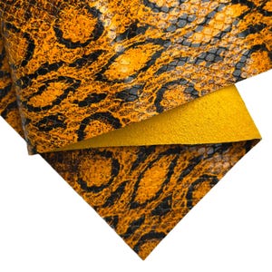 May include: Close-up of a textured leather material with a snakeskin pattern. The leather features a vibrant orange and black design, with a yellow suede backing visible. This material is suitable for crafting.