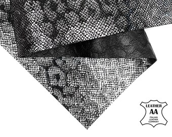 Op de afbeelding: Close-up van textiel leer in zwart en zilver. Het materiaal heeft een slangenleerachtig patroon. Het logo van de Italian Leather Company is rechtsonder zichtbaar.