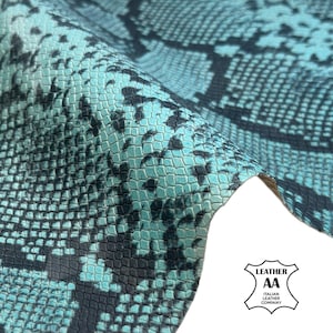 May include: Close-up of a textured leather material with a snakeskin pattern. The leather features a teal and black colour scheme. The image includes the "LEATHER AA ITALIAN LEATHER COMPANY" logo.