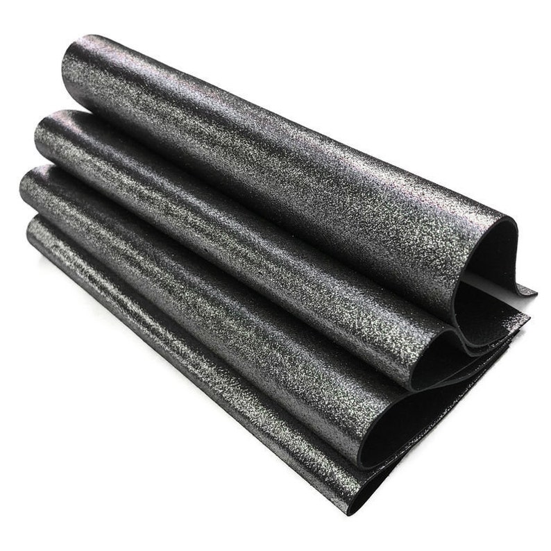 May include: A stack of rolled, dark gray material with a speckled, glittery finish. The material is folded over itself, revealing a black underside. The rolls are stacked on top of each other, creating a layered effect.