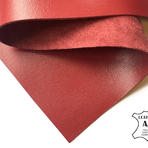 Könnte beinhalten: Nahaufnahme einer roten Lederplatte mit strukturierter Oberfläche. Das Leder ist umgefaltet und zeigt die Wildleder-ähnliche Unterseite. Das Logo der Italian Leather Company befindet sich unten rechts.