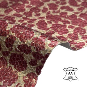 May include: Close-up of a piece of textured leather with a floral pattern in burgundy and beige. The leather is folded, revealing the underside. The image includes the logo of the Italian Leather Company.