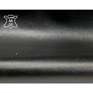 May include: Close-up of black leather with a textured surface. The image features the "AA Italian Leather Company" logo in white. The leather appears to be high-quality and suitable for various crafting projects.