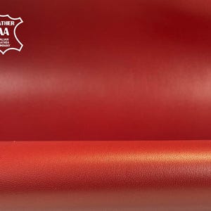 Puede incluir: Primer plano de cuero rojo con una textura suave. La imagen presenta un logotipo en la esquina superior izquierda que dice "LEATHER AA ITALIAN LEATHER COMPANY". El cuero parece ser de alta calidad y adecuado para varios proyectos de artesanía.