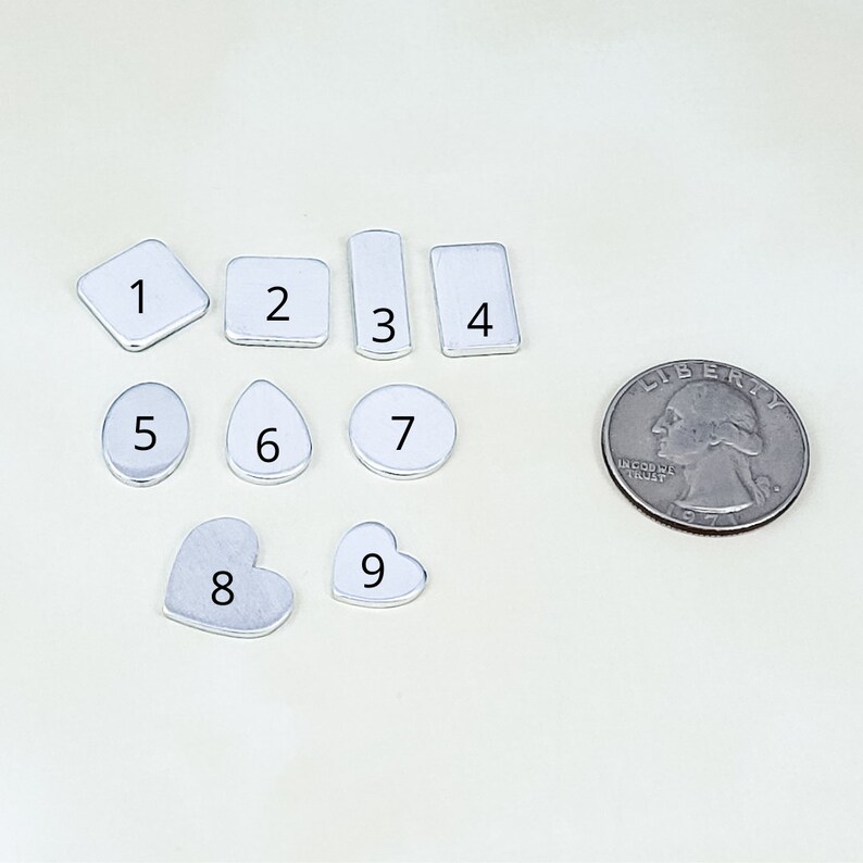 Puede incluir: Una colecci&oacute;n de nueve peque&ntilde;as piezas met&aacute;licas plateadas de varias formas, incluyendo cuadrados, rect&aacute;ngulos, c&iacute;rculos, gotas y corazones. Se incluye una moneda de 25 centavos estadounidense para comparar el tama&ntilde;o. Cada pieza est&aacute; numerada del 1 al 9.