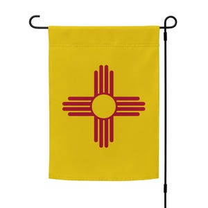 May include: A yellow garden flag with a red Zia symbol, a traditional symbol of the Pueblo people of New Mexico.