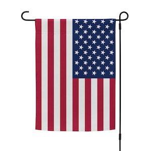 May include: A small American flag on a black metal pole. The flag is red, white, and blue with 13 stripes and 50 stars.