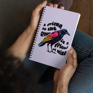 May include: A purple spiral notebook with a colorful crow illustration and the text "a friend to the crows is a friend of mine".