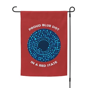 May include: A red garden flag with a blue circle design and the text "Proud Blue Dot in a Red State".