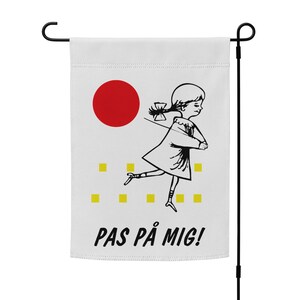 May include: A white garden flag with a black and white illustration of a girl running with a red circle behind her. The text "PAS PÅ MIG!" is printed in black at the bottom of the flag.