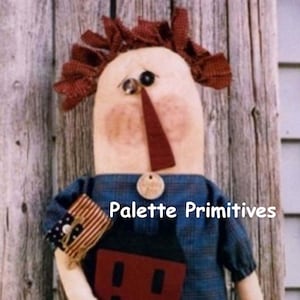 May include: A handmade rag doll with red and white checkered hair, a red nose, and a blue plaid shirt. The doll is holding a red and white striped bag with a small American flag on it. The doll is standing in front of a wooden background. The text "Palette Primitives" is written in white letters on a blue background.