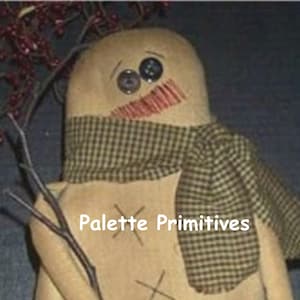 May include: A handmade rag doll snowman with a brown and white plaid scarf. The doll has a stitched smile and button eyes. The doll is holding a twig in its hand. The text "Palette Primitives" is visible on the doll's chest.