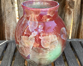 May include: A red ceramic vase with a floral pattern. The vase has a round body and a wide opening.