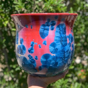 May include: A red and blue ceramic planter with a speckled glaze. The planter has a wide mouth and a rounded bottom.