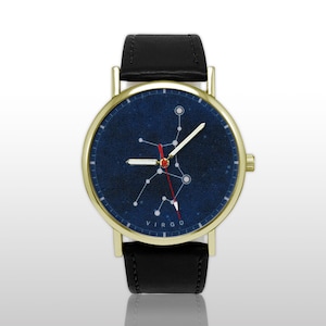 May include: A gold-coloured wristwatch with a black leather strap. The watch face displays a dark blue background with a white constellation design and the word "VIRGO". The hands are white and red.
