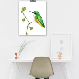 May include: A watercolour painting of a green hummingbird perched on a branch with green leaves. The hummingbird has a long, thin beak and a white throat.