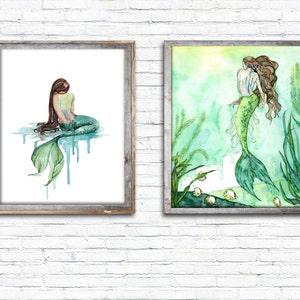 May include: Two framed watercolor paintings of mermaids. The first painting shows a mermaid sitting with her tail in the water. The second painting shows a mermaid swimming in a green and blue underwater scene.