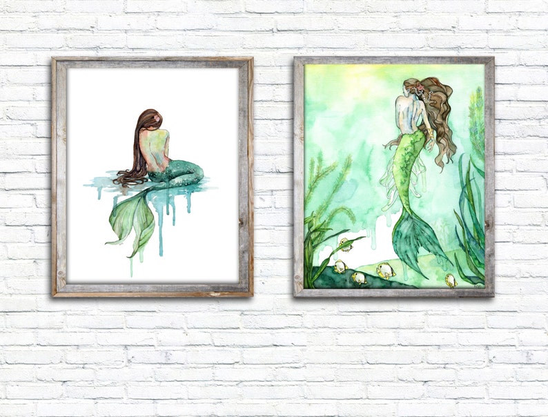 May include: Two framed watercolor paintings of mermaids. The first painting shows a mermaid sitting with her tail in the water. The second painting shows a mermaid swimming in a green and blue underwater scene.