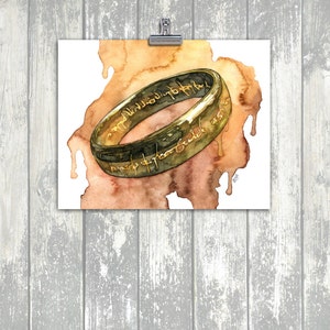 K&ouml;nnte beinhalten: Ein Aquarellbild eines goldenen Rings mit einer Inschrift in Schwarz. Der Ring befindet sich auf einem braunen und orangefarbenen Aquarellhintergrund.