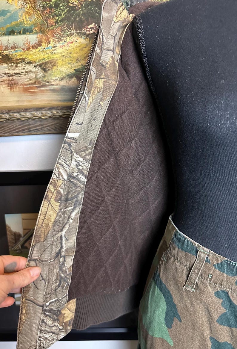 Puede incluir: Una chaqueta de camuflaje con forro acolchado marr&oacute;n y un pantal&oacute;n de camuflaje a juego. La chaqueta tiene cierre de cremallera y cuello acanalado marr&oacute;n. El estampado de camuflaje presenta tonos de marr&oacute;n, verde y beige.