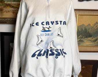 May include: White quarter-zip sweatshirt with the text "ICE CRYSTAL" and "CLASSIC 1995" in blue. The design includes illustrations of ice skates and ice skaters. The sweatshirt has a high collar and ribbed cuffs.