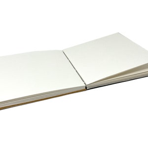 May include: A blank, white, square-shaped sketchbook with a brown spine and pages. The book is open to reveal the blank pages.