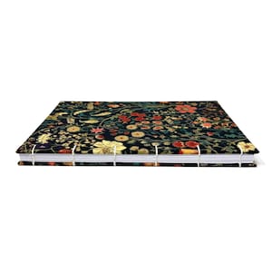 May include: A rectangular notebook with a black cover featuring a dense floral pattern in shades of red, yellow, and green. The book is bound with visible white thread stitching along the spine, showcasing a coptic stitch binding style.