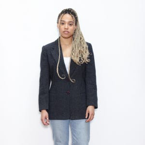 May include: A black and white checkered blazer with a single button closure. The blazer has a fitted silhouette and is worn by a person with long blonde braids.