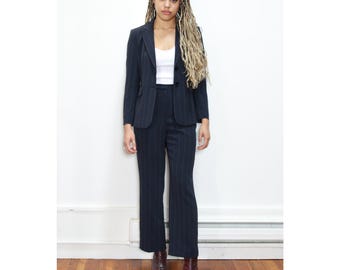 May include: A navy blue pinstripe suit with a blazer and pants. The blazer has a single button closure and the pants have a straight leg.