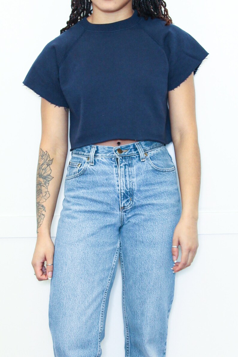 May include: A navy blue cropped sweatshirt with short sleeves and a relaxed fit.