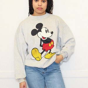 May include: A gray sweatshirt with a vintage Mickey Mouse graphic. The sweatshirt has long sleeves and a crew neck.
