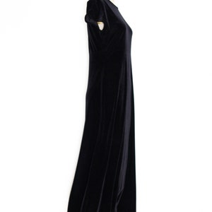 Puede incluir: Un vestido maxi de terciopelo negro con mangas cortas. El vestido est&aacute; sobre un fondo blanco.