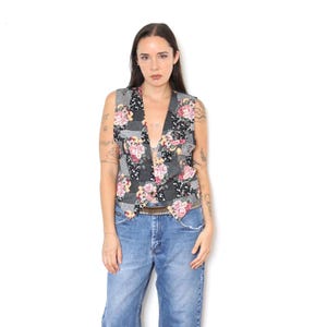 Peut inclure: Un gilet sans manches présentant un motif patchwork composé de tissu à carreaux noir et blanc et de motifs floraux dans des tons de rose, jaune et vert. Le gilet possède une encolure en V, une fermeture à un bouton et un ourlet pointu à la taille.