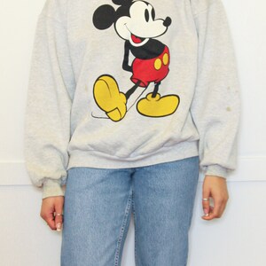 May include: A gray sweatshirt with a cartoon image of Mickey Mouse in a red and yellow outfit.