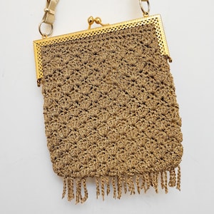 May include: A gold crocheted purse with a gold metal frame and a chain strap. The purse has a fringe detail at the bottom.