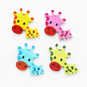May include: Four wooden giraffe buttons with different colored spots. The giraffes are yellow, pink, blue, and green. Each giraffe has a red nose and black eyes.
