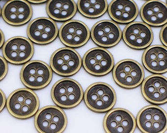 May include: A large group of antique gold metal buttons with four holes each. The buttons are scattered on a white surface.