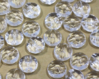 May include: A large group of clear glass beads with a textured surface. The beads are round and have a slightly flattened shape.