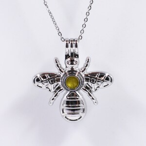 May include: A silver bee charm necklace with a clear glass orb in the center. The bee has detailed wings and a textured body.