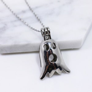 May include: A silver ghost-shaped locket necklace. The locket is open and has a small hole in the centre of the ghost's face.