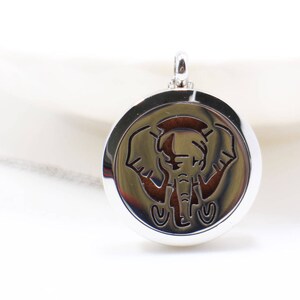 May include: Silver pendant with an elephant design. The pendant is round and has a hole at the top for a chain.