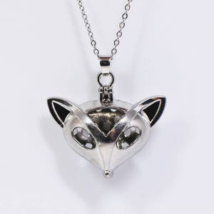 May include: A silver fox-shaped locket necklace with a hinged opening. The locket is detailed with black accents around the eyes and ears.