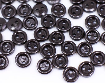 May include: A large group of brown wooden buttons with two holes each. The buttons are scattered on a white surface.